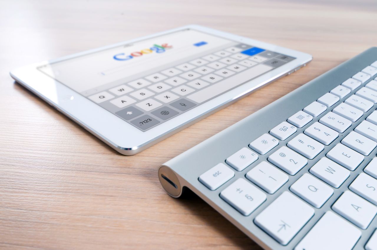 brand-01 A modern tablet displaying a search engine logo next to a wireless keyboard on a wooden desk.